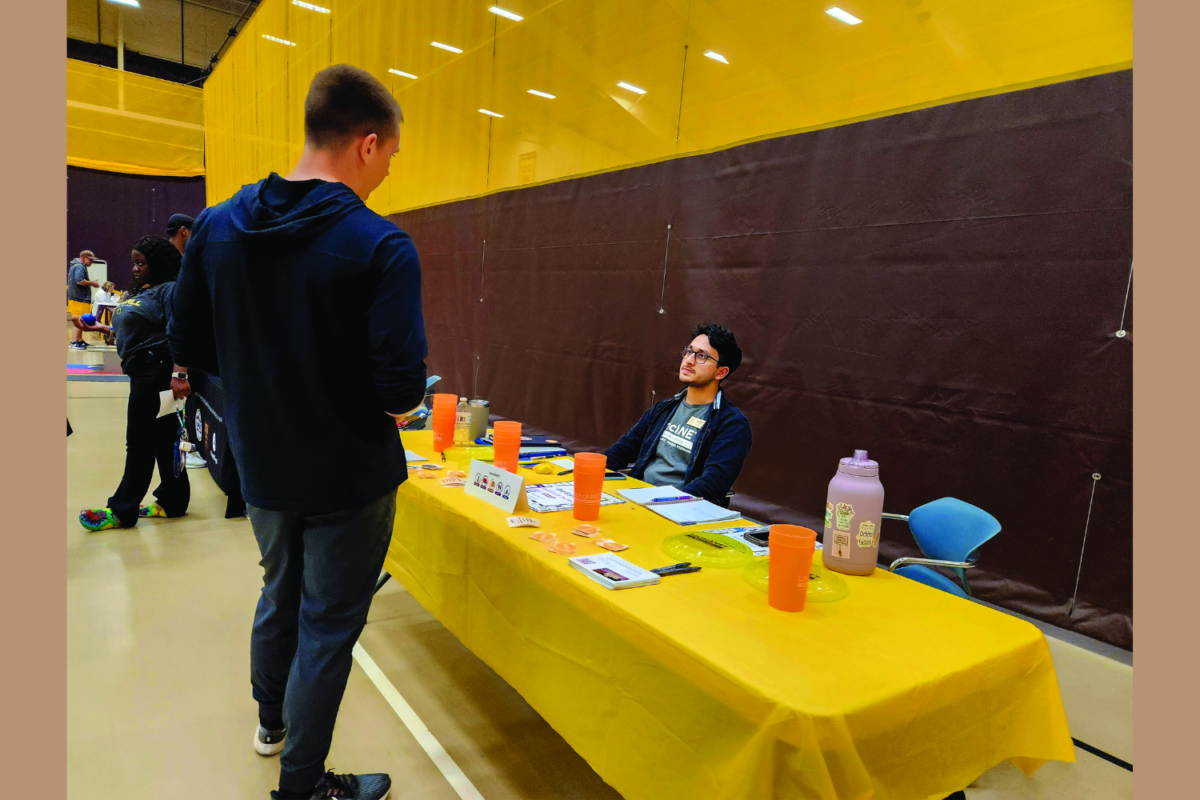 One of the vendors speaks to a student at Wellfest regarding of the six dimensions of wellness.
