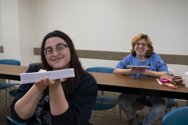 Left to right: Bella Issa and Cori Slaw show the initial stage of the books they are binding. 