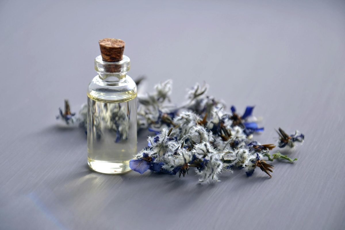 A bottle of perfume displayed next to a bunch of lavender