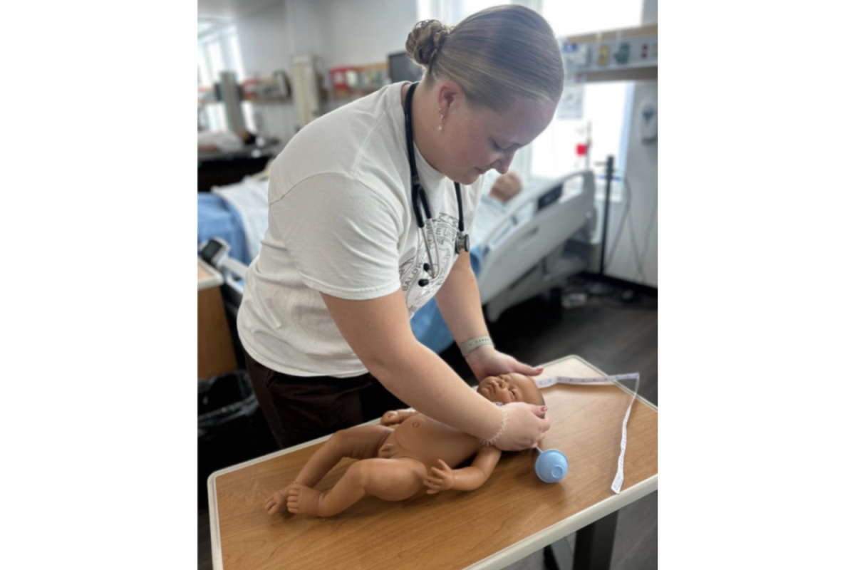 Senior nursing student Ellen Fox with an infant simulator.