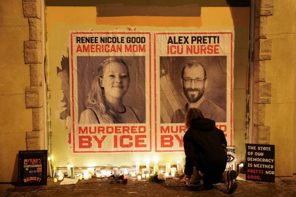A person kneels near posters with images of Renee Nicole Good and Alex Pretti, after they were fatally shot in two separate incidents by federal immigration agents, following a vigil in Minneapolis, Minnesota, U.S., January 28, 2026. REUTERS/Seth Herald