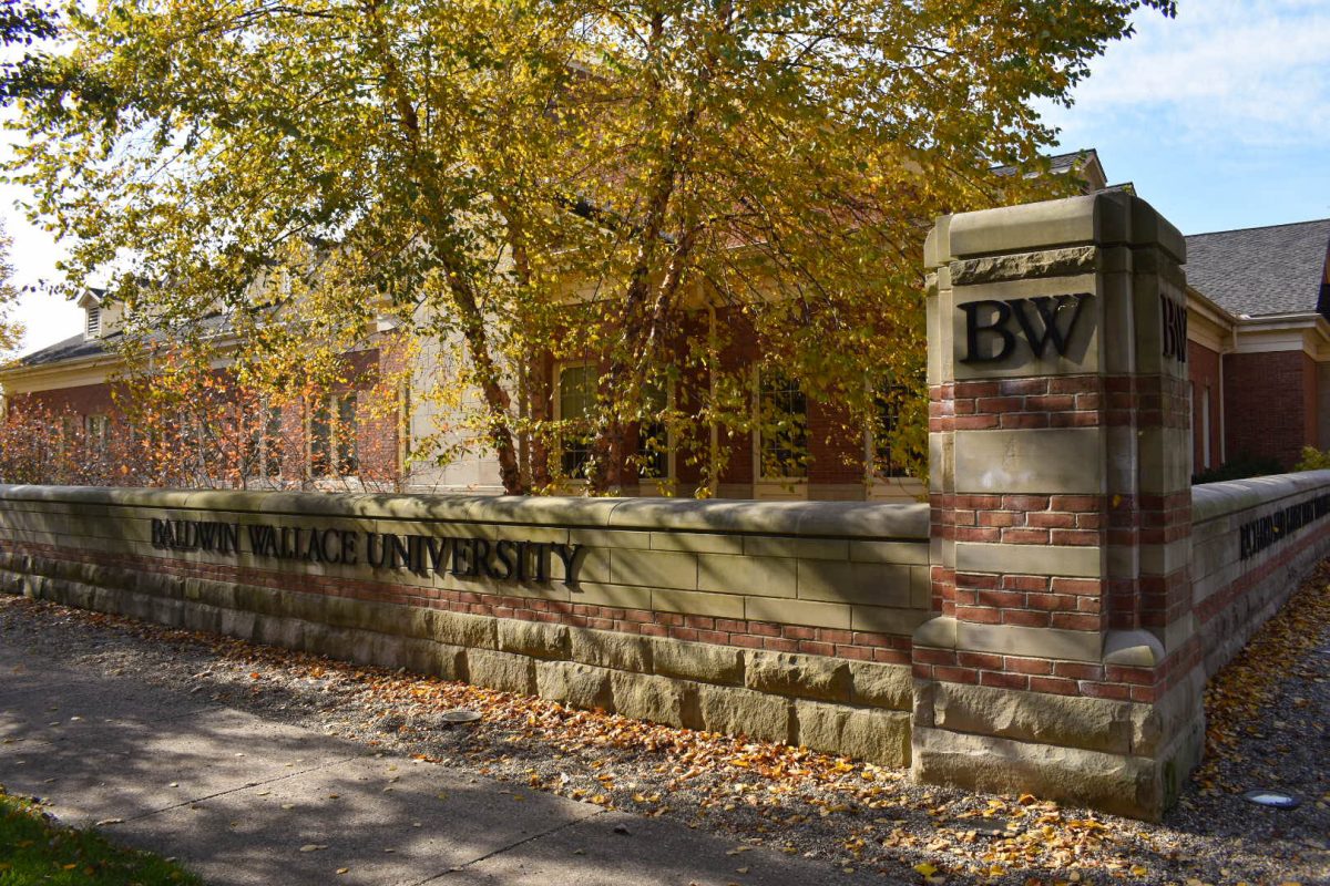 A Baldwin Wallace University sign stands along the campus entrance, framed by autumn leaves, in Berea, Ohio.
