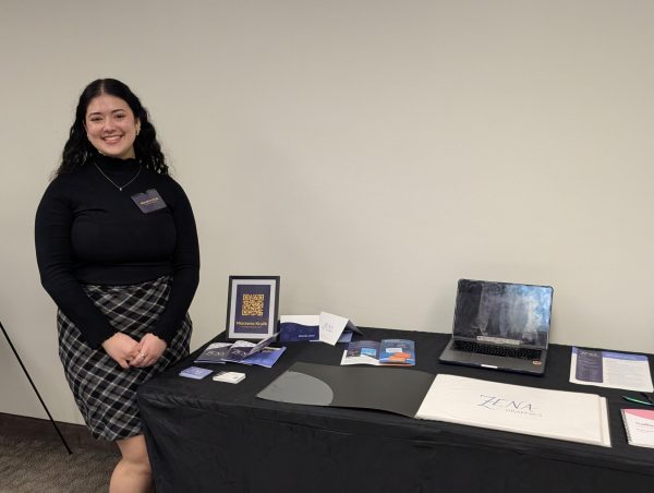 Marzena Krulik poses next to her booth at the 2026 Graphic Design Senior Exhibition.